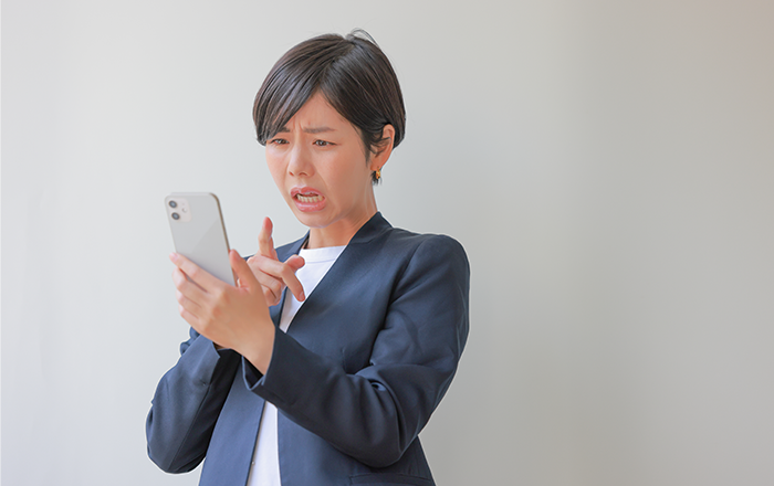 スマートフォンを持って困っている女性のイメージ